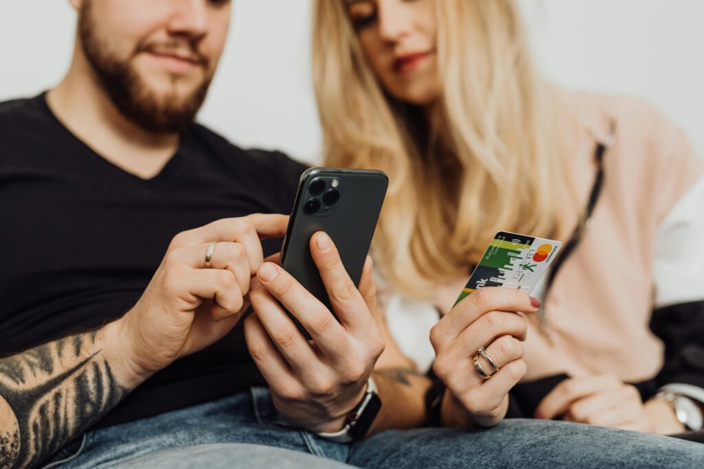 Consumidores utilizando celular e cartão de crédito para realizar compras online durante uma data sazonal