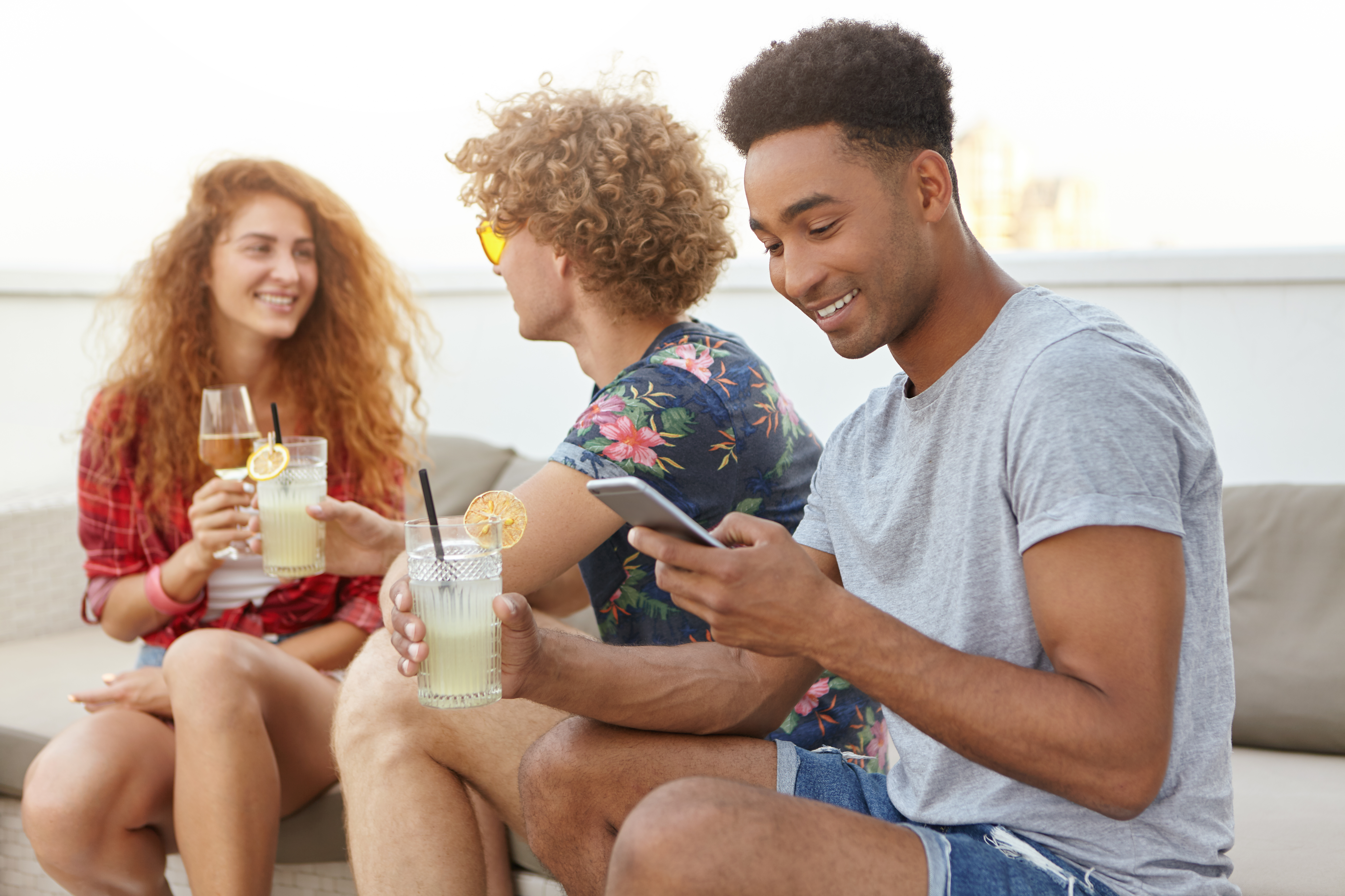 Grupo de amigos reunidos ao ar livre usando celular e brindando, representando momentos de lazer e consumo em datas sazonais do Calendário E-commerce 2026.